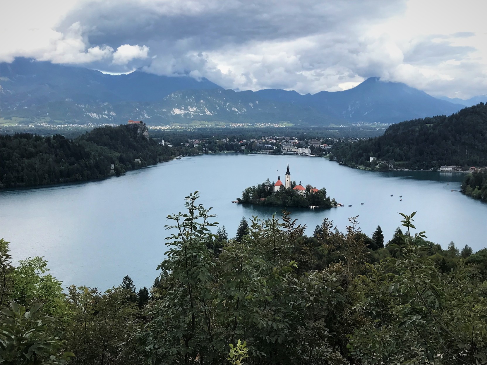 overhead shot of Lake Bled, Slovenia with island in center of lake and mountains in background