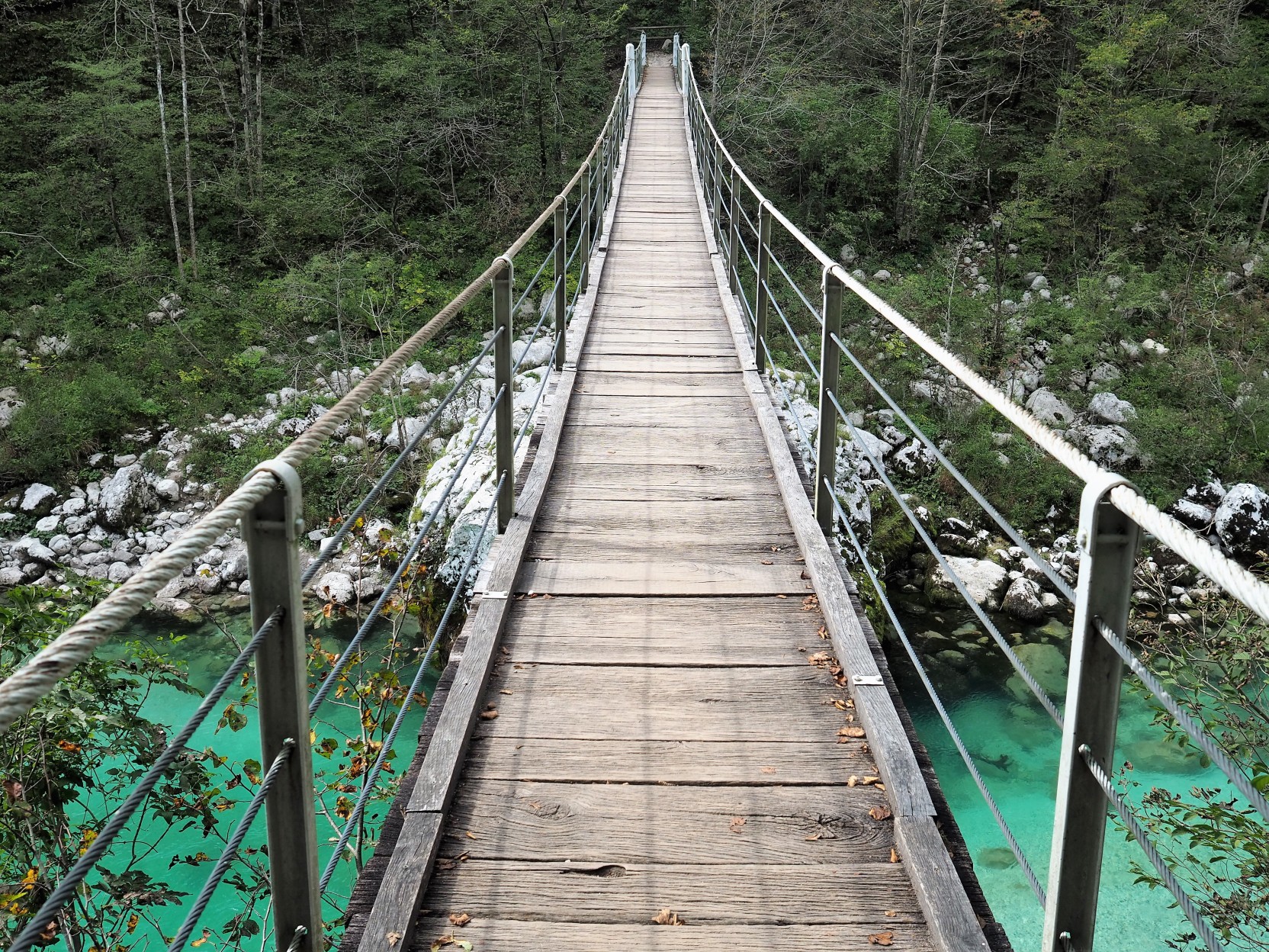 wooden suspension bridge over green Soca River in Slovenia